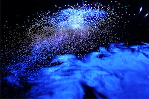 <b>Oceanic Galaxy:</b> Different materials have been researched to make the laser beam visible.  The most intriguing result was achieved using the tiny droplets from a spray bottle, creating the effect of a strange, wild galaxy in the deep blue swirls of an ocean. The turbulent twist of a silken thread within the laser fan additionally obfuscates the process in which this photograph was created.